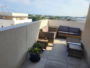 A rooftop terrace with wicker furniture, potted plants, and a view of the cityscape. - Luminous Cocoon - All-Around Comfort - Sleeps 4 to 6 (Montpellier)