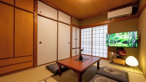 A traditional Japanese room with tatami flooring, a low table, cushions, sliding doors, and a television. - Entire 85-square-meter Property for Rent | Experience Traditional Japanese-Style Rooms | 5 minutes from Shin-Osaka, 38 minutes direct to Kyoto | A base for sightseeing in the Kansai region near a shopping district (大阪市)