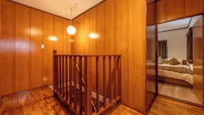 A room with wooden panel walls, a wooden railing, and a bed with pillows and a blanket. - Entire 85-square-meter Property for Rent | Experience Traditional Japanese-Style Rooms | 5 minutes from Shin-Osaka, 38 minutes direct to Kyoto | A base for sightseeing in the Kansai region near a shopping district (大阪市)