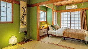A traditional Japanese-style room with tatami flooring, a bed with a wooden frame, a shoji screen, and a hanging air conditioner. - Entire 85-square-meter Property for Rent | Experience Traditional Japanese-Style Rooms | 5 minutes from Shin-Osaka, 38 minutes direct to Kyoto | A base for sightseeing in the Kansai region near a shopping district (大阪市)