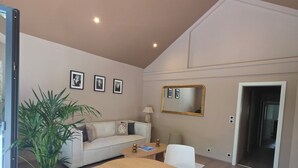 A modern living room with a sofa, a dining table, and a potted plant. - Alsace apartment adjacent to the Domaine de Pairis, Pets allowed, (Orbey)
