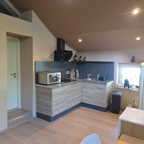 A modern kitchen with a built-in microwave, sink, and wooden cabinetry. - Alsace apartment adjacent to the Domaine de Pairis, Pets allowed, (Orbey)