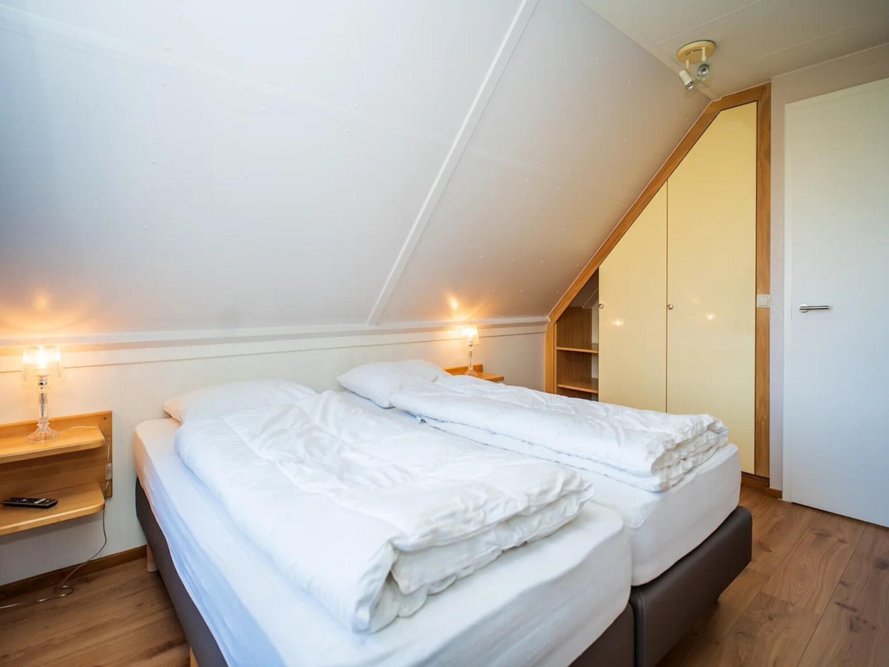 Une chambre à coucher comprenant un lit, des tables de chevet, une armoire et un luminaire au plafond.