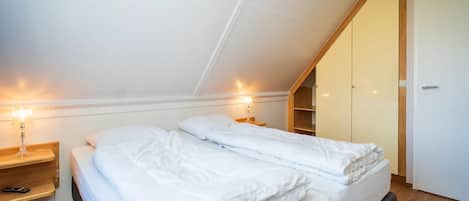 A bedroom with a bed, bedside tables, a wardrobe, and a ceiling light.