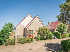 Ein Wohnhaus mit Satteldach, Eingangstür und Auffahrt.