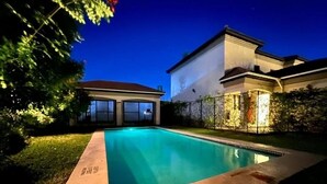 A swimming pool with a house in the background. - Apartment in Roma (Lusaka)