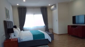 A modern bedroom with a bed, bedside tables, a TV, and a red bench. - Apartment in Roma (Lusaka)