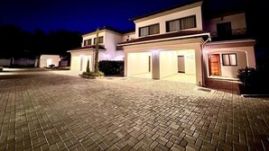 A modern two-story house with a paved driveway and illuminated entrance. - Apartment in Roma (Lusaka)