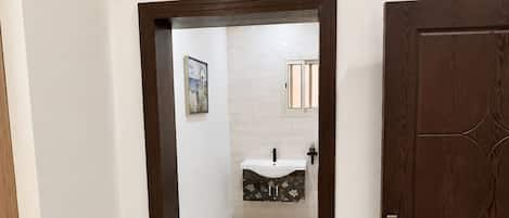 Un pasillo que conduce a un baño con lavabo y espejo.