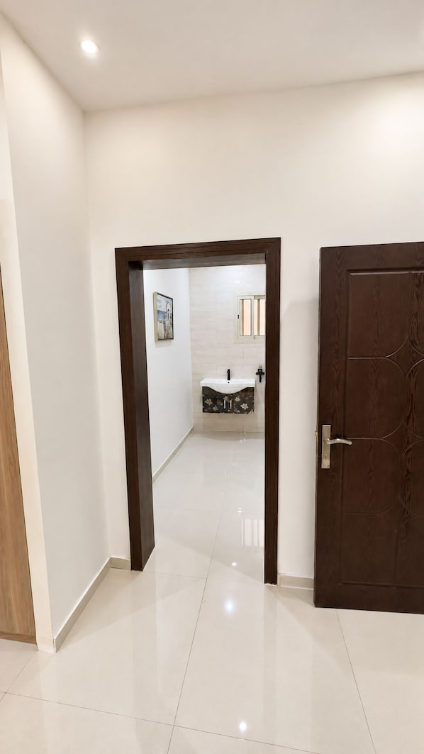 A hallway leading to a bathroom with a sink and mirror. - Dome Hotel El Nuzha (Riyadh)