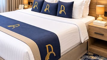 A hotel room with a bed, a nightstand, a lamp, and a patterned carpet.