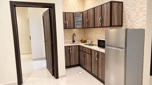 A modern kitchen with dark wood cabinets, a stainless steel refrigerator, and a microwave. - Dome Hotel El Nuzha (Riyadh)