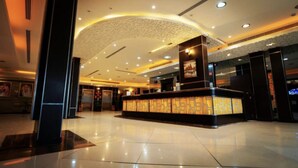 A hotel lobby with a reception desk, a large chandelier, and a patterned wall. - Dome Hotel Service Apartments (Riyadh)