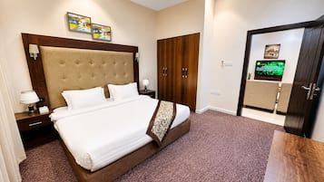 A hotel room with a large bed, a wardrobe, a television, and artwork on the wall.