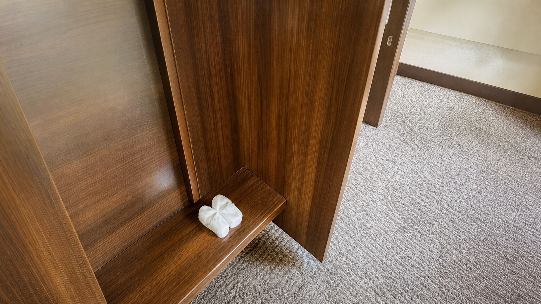 A wooden floor with a carpeted area and a small white object on the floor.