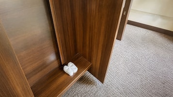 A wooden floor with a carpeted area and a small white object on the floor.