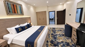 A hotel room with a bed, a desk, a wardrobe, and a bathroom visible through an open door. - Dome Hotel El Nuzha (Riyadh)