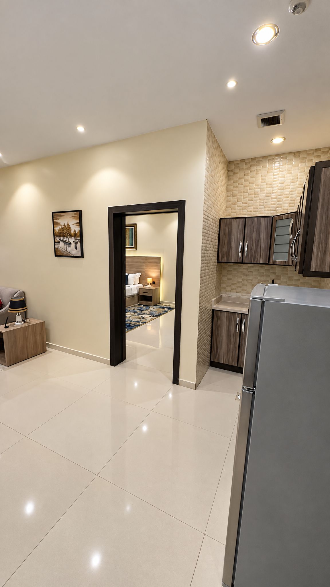 A modern kitchen with a refrigerator, cabinets, and a tiled backsplash.