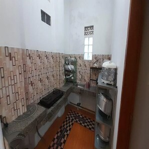 A compact kitchen with patterned tiles, a sink, a drying rack, and a small window. - Cozzy Darmaga Palayangan Pangalengan (pangalengan)