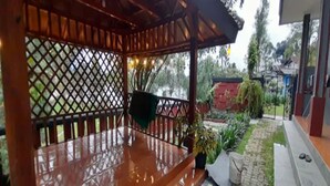 A wooden deck with a table and chairs, surrounded by a lattice fence and potted plants. - Cozzy Darmaga Palayangan Pangalengan (pangalengan)