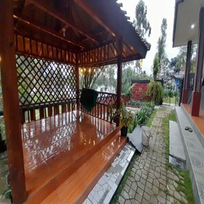 A wooden deck with a table and chairs, surrounded by a lattice fence and potted plants. - Cozzy Darmaga Palayangan Pangalengan (pangalengan)