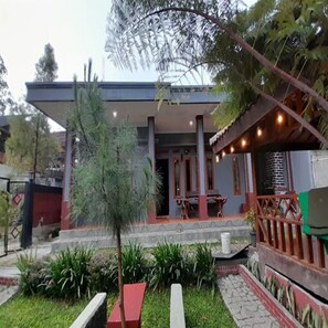 A building with a covered patio area, a small tree, and a well-maintained garden. - Cozzy Darmaga Palayangan Pangalengan (pangalengan)