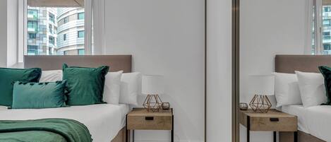Habitación de hotel con cama, mesitas de noche, un espejo y vistas a edificios.