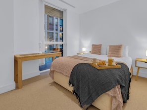A bedroom with a bed, bedside tables, a window with a view, and a tray with breakfast items. - Canary Heights 2bed by Interhome (London)