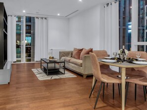 A modern living room with a sofa, a dining table set for two, and a coffee table. - Canary Heights 2bed by Interhome (London)