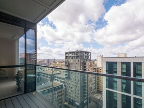 En hög byggnad med utsikt över andra byggnader och en delvis molnig himmel.