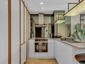 A modern kitchen with a central island, built-in appliances, and a view of the living area. - Stratford Loft by Interhome (London East)