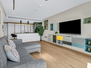 A modern living room with a grey sectional sofa, a flat-screen TV, and a minimalist entertainment unit. - Stratford Loft by Interhome (London East)