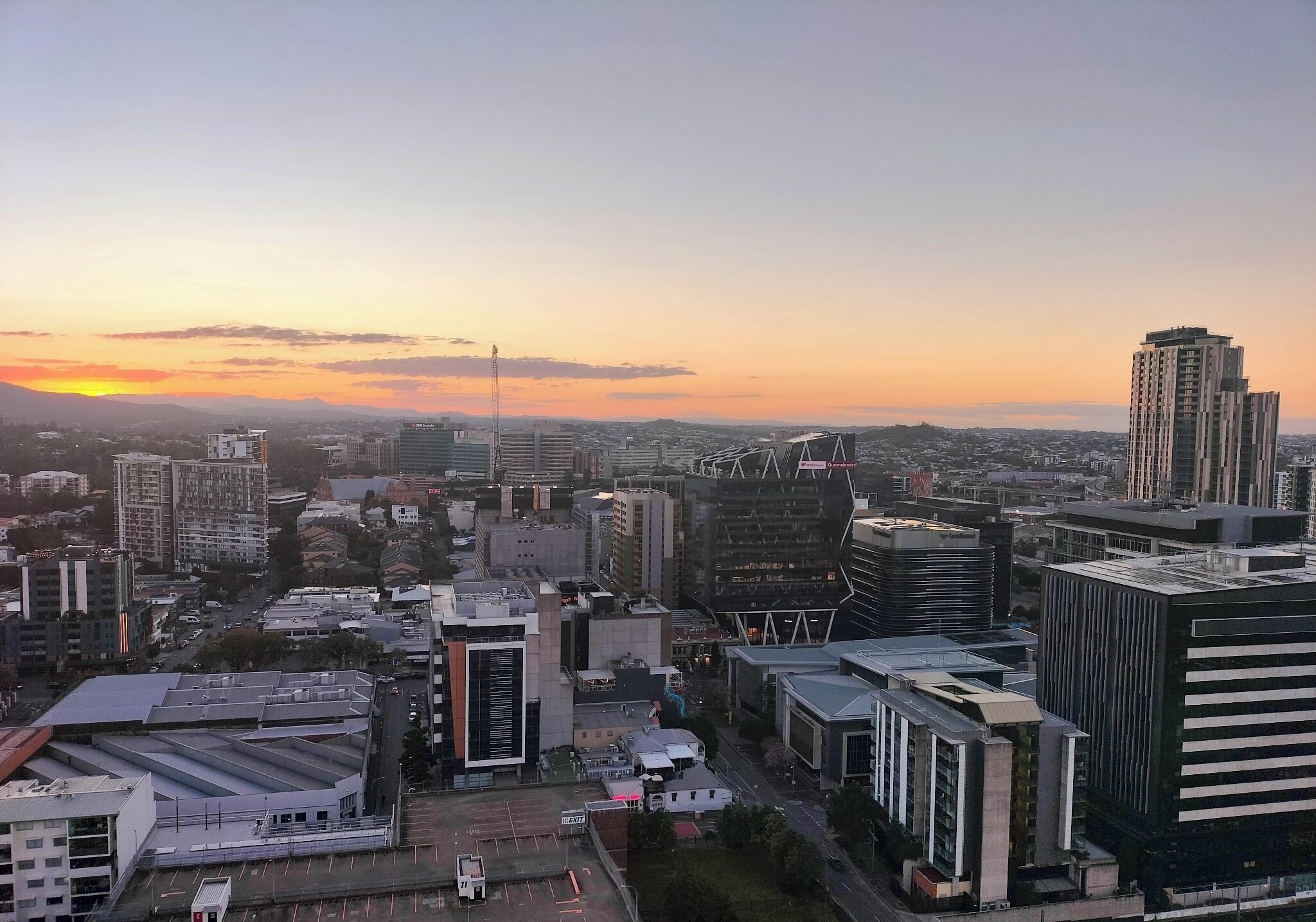 Un paisaje urbano con edificios modernos, cielo despejado y una puesta de sol.