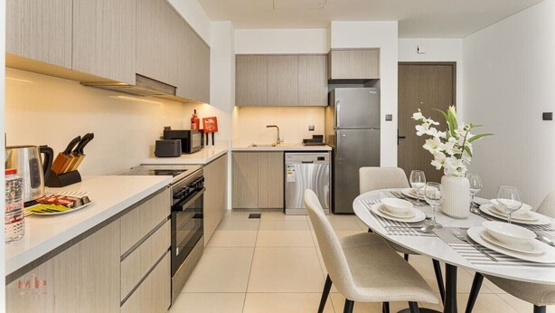 A modern kitchen with a dining area, featuring a stainless steel refrigerator, a microwave, and a built-in oven. - Madely | Opulent Condo Act Two | Burj Khalifa (Dubai)