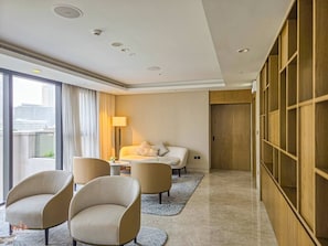 Ein Hotelzimmer mit einem Bett, zwei Sesseln, einem kleinen Tisch, einer Lampe und Blick auf die Stadt.