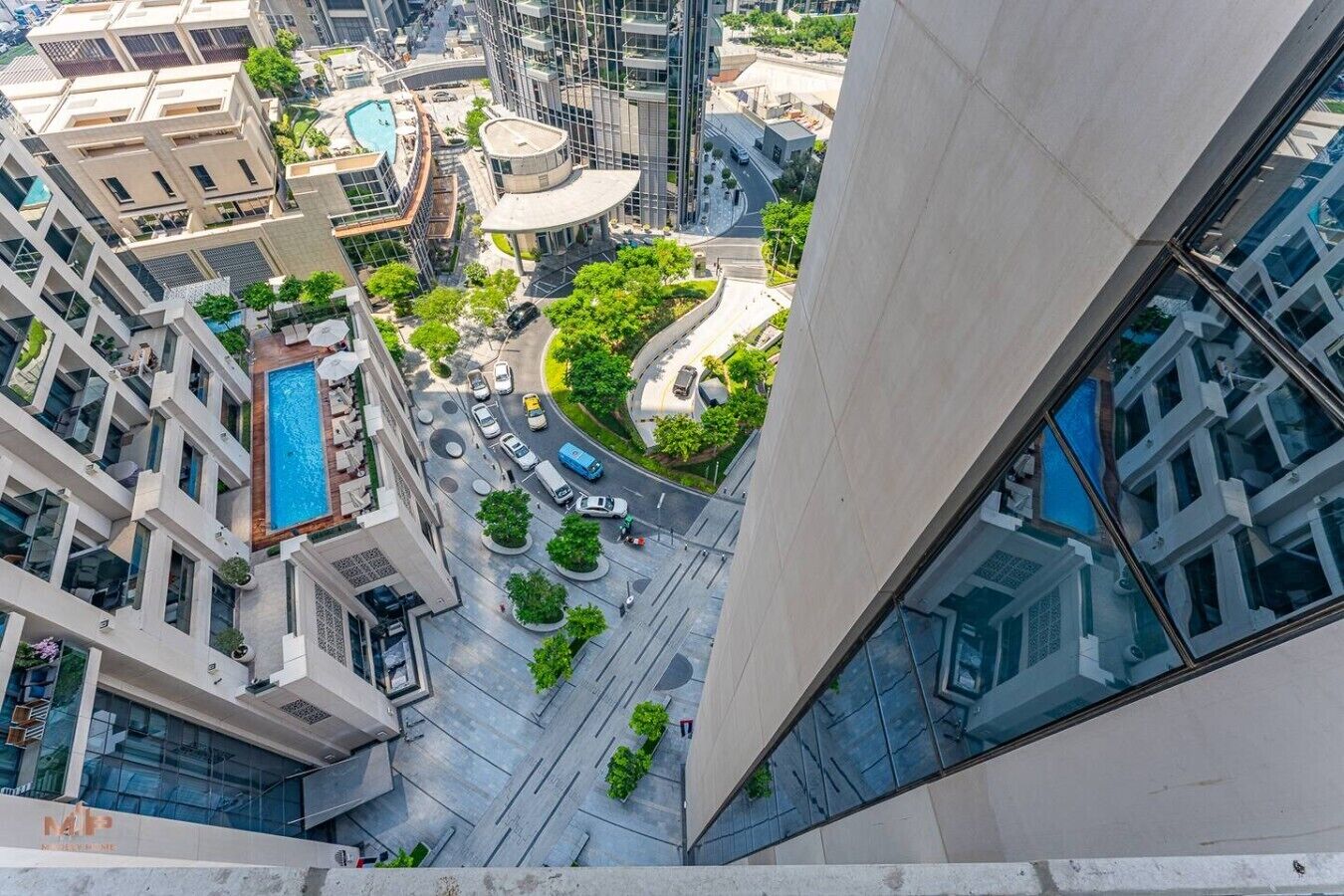 A high-rise building with a pool, a roundabout, and a mix of residential and commercial buildings.
