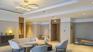 A modern lobby with a sofa, chairs, a coffee table, and a bench. - Madely | Opulent Condo Act Two | Burj Khalifa (Dubai)