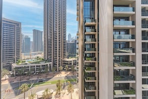 Ein Hochhaus mit mehreren Balkonen, ein angelegter Garten mit Palmen und freie Sicht auf die umliegende Skyline.