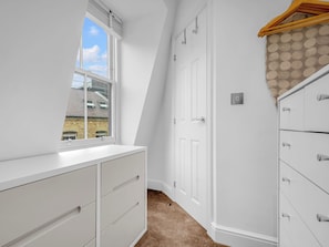 A room with a white dresser, a closet with multiple drawers, a window with blinds, and a door. - Spitafields Apartment by Interhome (Clerkenwell)