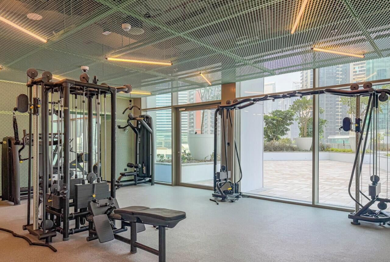 A gym with various exercise equipment, large windows, and a view of the outside.