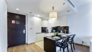 Una cucina moderna con zona pranzo, pavimento in legno e una porta scura.