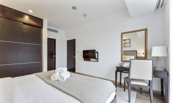A hotel room with a bed, a desk, a chair, a TV, and a mirror. - Beautiful 1 bed | Jw Marriot | Sea view (Dubai)