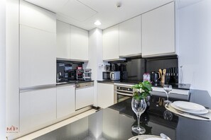 A modern kitchen with white cabinetry, a black countertop, and a glass wine glass on the table. - Beautiful 1 bed | Jw Marriot | Sea view (Dubai)
