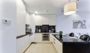 A modern kitchen with a central island, built-in appliances, and a dining area with a black countertop. - Beautiful 1 bed | Jw Marriot | Sea view (Dubai)