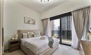 A bedroom with a large bed, a nightstand, a window with curtains, and a city view. - Madely | Chic Act One Haven | Burj Khalifa (Dubai)