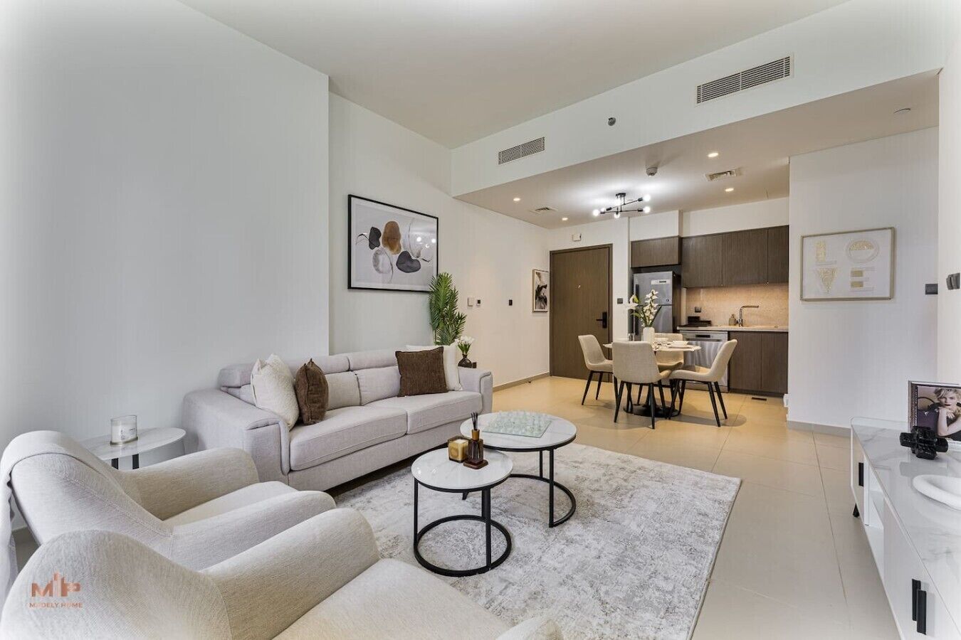 A modern living room with a sofa, two armchairs, a coffee table, and a dining area with chairs and a table.