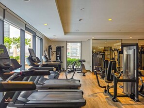 A gym with treadmills, weight machines, and exercise equipment. - Madely | Chic Act One Haven | Burj Khalifa (Dubai)