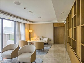 Ein Hotelzimmer mit einem Bett, zwei Sesseln, einem kleinen Tisch, einer Lampe und Blick auf die Stadt.