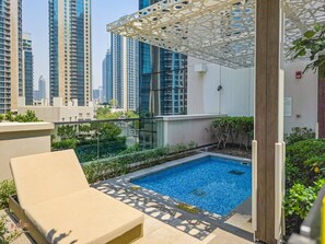 A rooftop swimming pool with a glass balustrade, a lounge chair, and a view of high-rise buildings. - Madely | Chic Act One Haven | Burj Khalifa (Dubai)