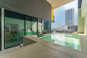 Ein modernes Interieur mit einem gläsernen Essbereich, einem Pool und Blick auf die umliegenden Gebäude.